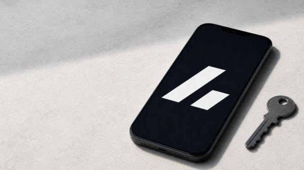 Ein Smartphone mit dem weißen Bitvavo-Zeichen auf schwarzem Bildschirm liegt auf hellem Stein, daneben ein einzelner Metallschlüssel.