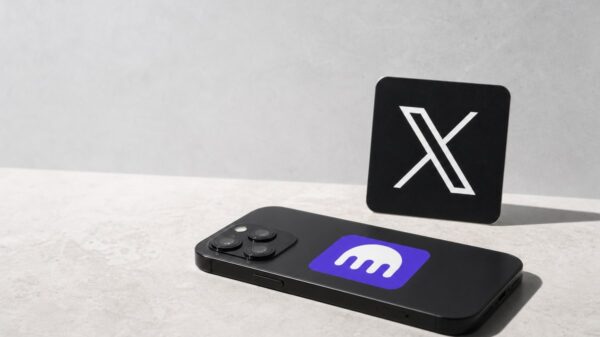 Ein Smartphone liegt mit der Rückseite nach oben auf hellem Stein, darauf das violette Kraken-Zeichen mit dem weißen Tintenfisch; dahinter steht ein schwarzer Aufsteller mit dem weißen X-Logo.