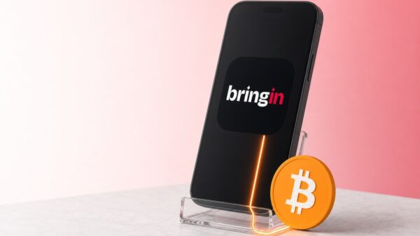 Ein schwarzes Smartphone steht in einem durchsichtigen Ständer und zeigt groß das Bringin-App-Symbol, davor lehnt eine orangefarbene Bitcoin-Münze, ein leuchtender Strich verbindet Münze und Telefon.