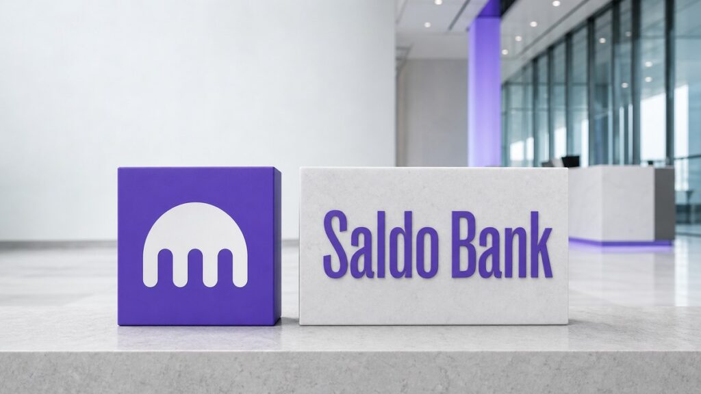 Auf einer hellgrauen Steinbank in einer modernen Bankhalle stehen ein violetter Würfel mit dem weißen Kraken-Zeichen und ein gleich hoher weißer Steinblock mit der violetten Wortmarke Saldo Bank nebeneinander.