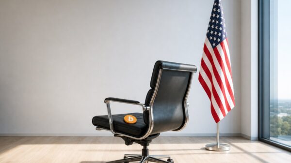 Ein leerer schwarzer Ledersessel steht in einem hellen Büro, auf seinem Sitz liegt eine orangefarbene Bitcoin-Münze, daneben hängt eine US-Flagge an einer Stange.