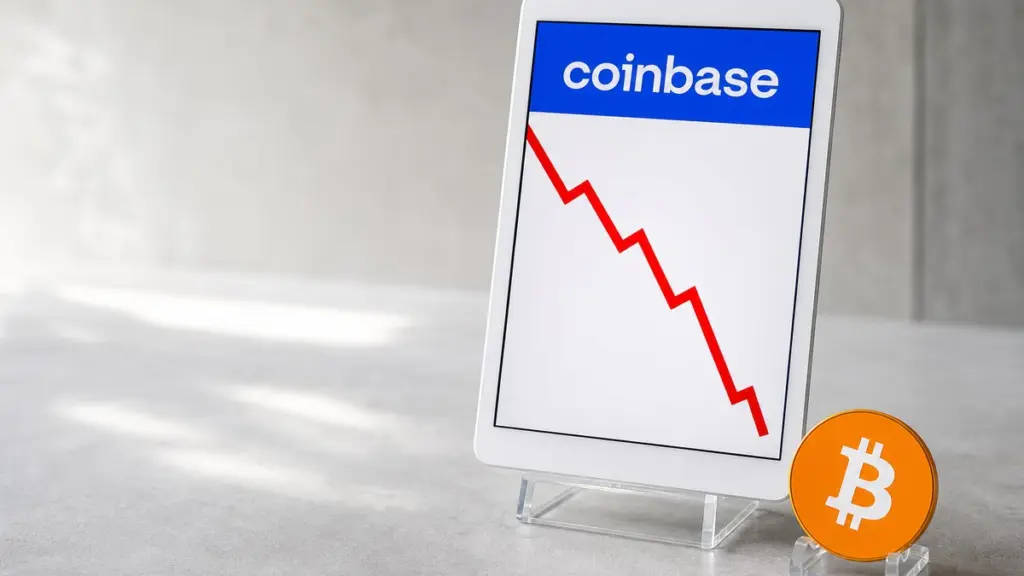 Weißes Tablet im Acrylhalter zeigt oben die Coinbase-Wortmarke und darunter eine steil fallende rote Linie, davor steht eine orangefarbene Bitcoin-Münze aufrecht in einem kleinen Halter.