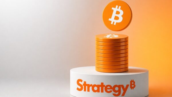 Stapel oranger Bitcoin-Münzen auf einem weißen runden Sockel mit dem orangen Strategy-Schriftzug, darüber schwebt eine weitere Bitcoin-Münze vor einem Verlauf von Hellgrau zu Orange.